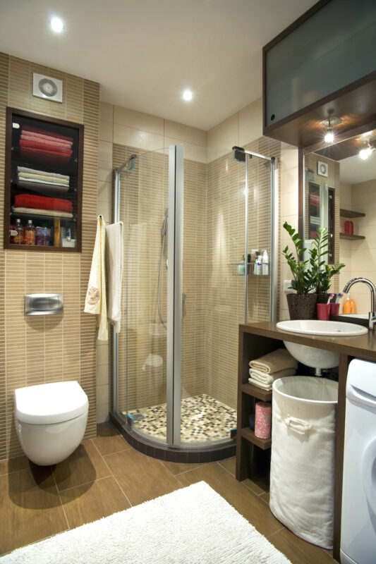 basement bathroom with clear shower enclosure, wall mounted toilet
